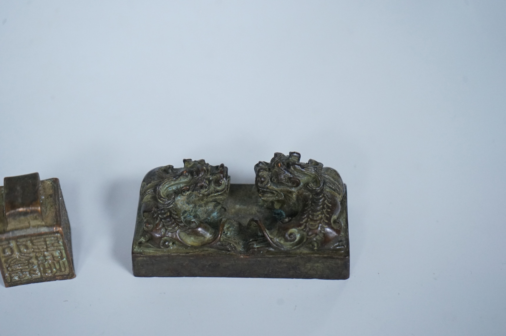 Four Chinese bronze seals, one in the form of two lion dogs, largest 7.5cm wide